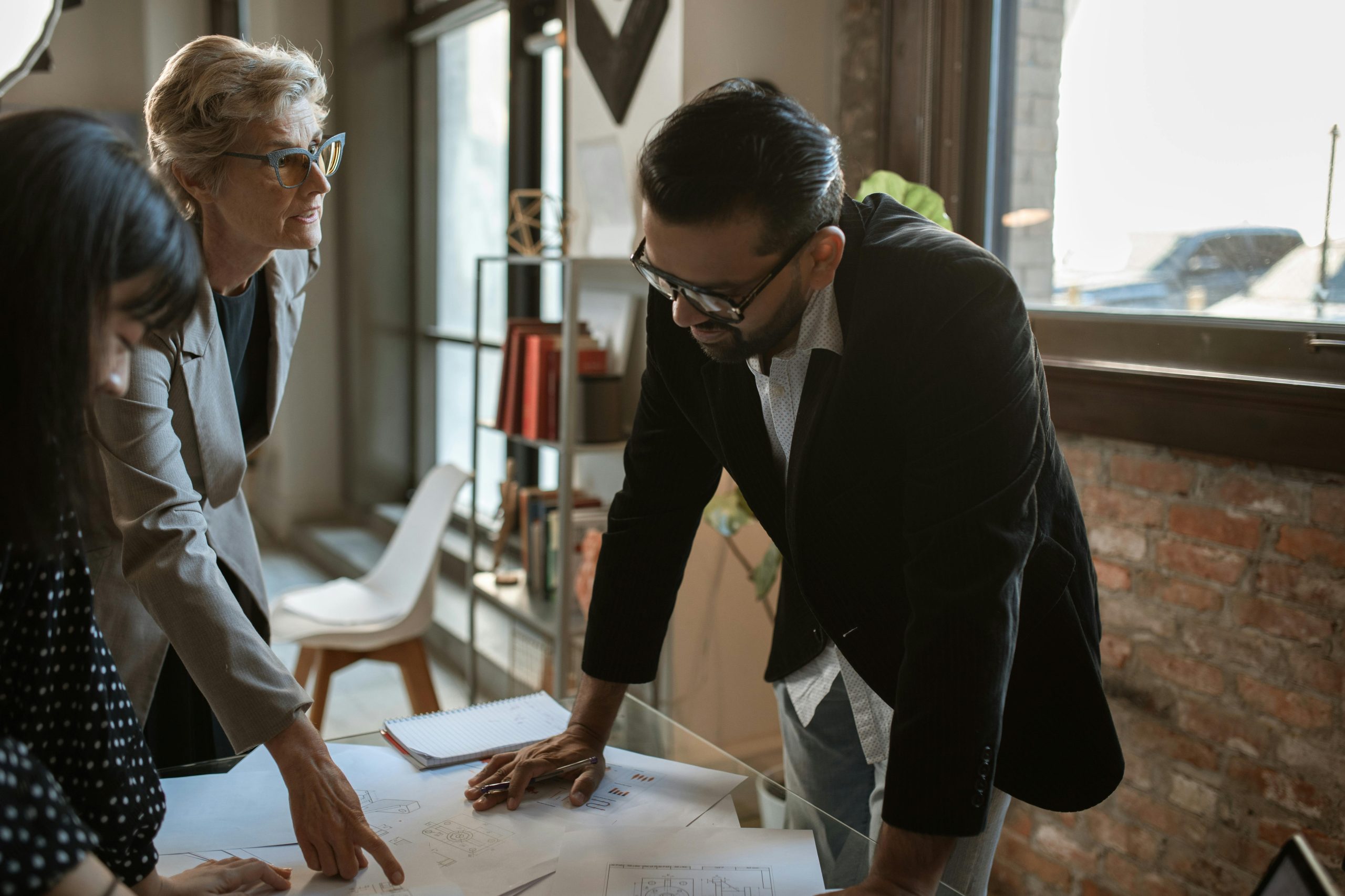 Two people discussing a document with mediator in the middle